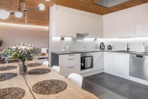 a kitchen with a wooden table and white cabinets at Arctic Holiday Apartments 5 in Rovaniemi