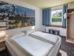 um quarto com uma cama grande e uma janela em B&B HOTEL Aachen-Würselen em Würselen