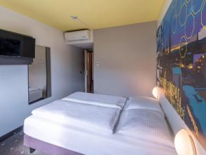 B&B HOTEL Aachen-Würselen في فورسلن: غرفة نوم بسرير ابيض مع لوحة على الحائط