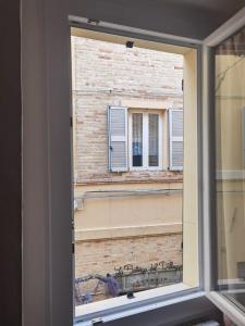 a window with a view of a brick building at Appartamento La Fisarmonica Recanati in Recanati