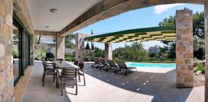 a patio with a table and chairs and a pool at Ouzo Stone House 1 with private pool in Plomari
