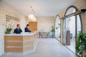 two men sitting at a counter in a lobby at Porto Drach Aparthotel & Suites in Porto Cristo +17 photos