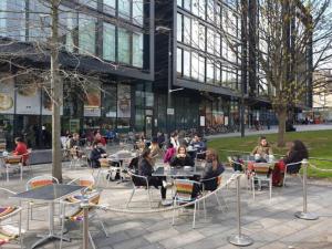 a group of people sitting at tables in front of a building at The Simpson - Luxury 2 bed - Private Parking in Edinburgh