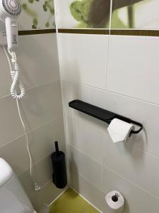 La salle de bains est pourvue d'un téléphone et de papier toilette sur le mur. dans l'établissement Hotel - cafe Naujoji Akmenė, à Naujoji Akmenė