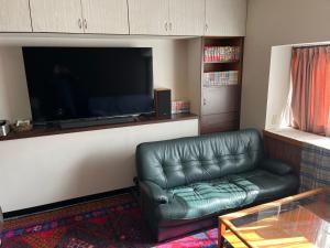 a living room with a leather couch and a flat screen tv at 離れの宿　かぶろの庭 in Matsukawa