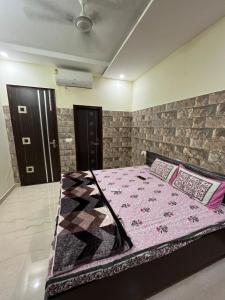 een slaapkamer met een bed met een roze quilt bij Odyin Apartment in Mohali