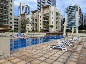 a swimming pool with lounge chairs and buildings at EasyGo - Al Samar 4 - 2 Bedroom & Maid in Dubai