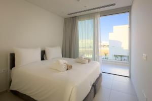 a bedroom with a large white bed with a large window at City Napa Seaview Villas - Villa 8 in Ayia Napa