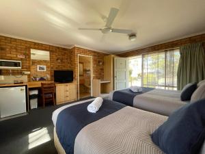 a hotel room with two beds and a kitchen and a television at Ocean View Motor Inn Merimbula in Merimbula