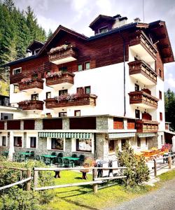 a building with balconies and tables in front of it at Hotel Gembro in Chiesa in Valmalenco