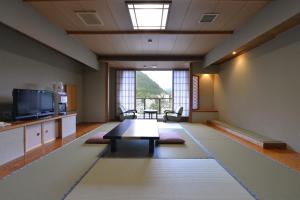 a living room with a table and a large window at Ooedo Onsen Monogatari Hotel New Shiobara in Nasushiobara