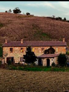 stary kamienny dom na polu obok wzgórza w obiekcie Molino della Tuoma w mieście San Quirico dʼOrcia