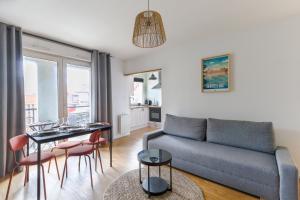 Una sala de estar con un sofá, una mesa y sillas. en Cocon Urbain à 2 pas de la Gare, en Nantes