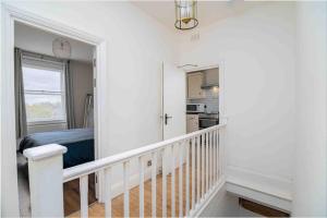 a white room with a staircase and a kitchen at Cosy 2 Bed Flat In East London in London