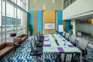 Flora Inn Hotel Dubai Airport في دبي: قاعة المؤتمرات مع طاولة وكراسي طويلة