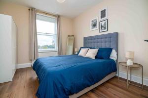 Un dormitorio con una cama azul y una ventana en Cosy 2 Bed Flat In East London en Londres