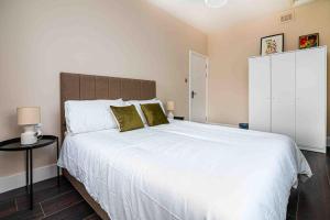 1 dormitorio con 1 cama blanca grande con almohadas verdes en Cosy 2 Bed Flat In East London en Londres