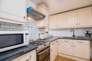 a kitchen with white cabinets and a white microwave at Cosy 2 Bed Flat In East London in London