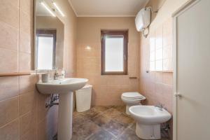 une salle de bain avec un lavabo, des toilettes et un miroir dans l'établissement Le Sabbie Bianche, à Calasetta 11 autres photos