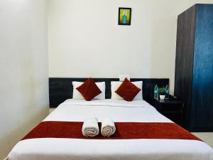 a bedroom with a large bed with towels on it at Orange Corner Hotel, MONTHLY STAY AVAILABLE in Yelahanka