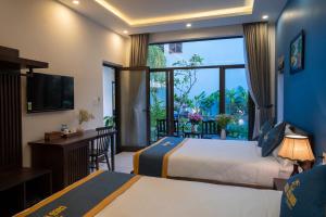 um quarto de hotel com duas camas e uma grande janela em Coco Island Villa em Hoi An