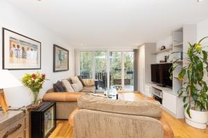 a living room with a couch and a tv at Immaculate 2BR Flat, Greenwich, 2 min Maze Hill St in London