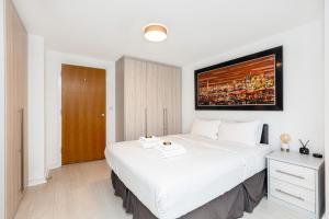 a bedroom with a white bed with a picture on the wall at Immaculate 2BR Flat, Greenwich, 2 min Maze Hill St in London