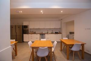a kitchen with two wooden tables and white cabinets at Gest in Mellieħa
