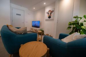 a living room with two blue chairs and a tv at Gest in Mellieħa