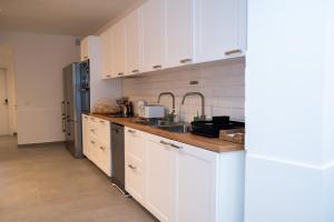a kitchen with white cabinets and a sink at Gest in Mellieħa