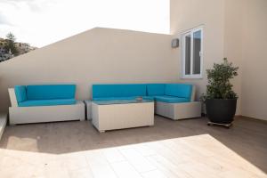 a patio with blue and white chairs and a table at Gest in Mellieħa