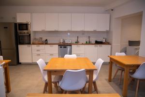 a kitchen with white cabinets and wooden tables and chairs at Gest in Mellieħa