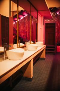 una fila di lavandini in un bagno con luci rosse di Mellow Ladies Hostel a Varkala