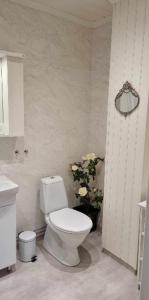 uma casa de banho com um WC e um vaso de flores em Wedbergs Rum em Säffle