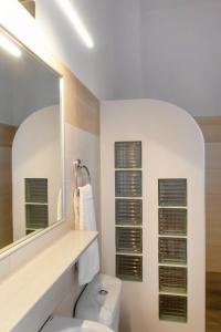 a bathroom with a white toilet and a mirror at Hotel Marilen in Alinda