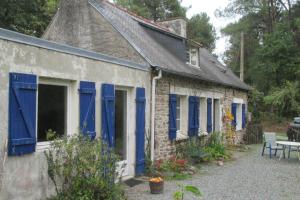 Casa de ladrillo antigua con persianas azules y patio en Maison forestière en Plouézec