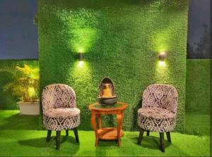 two chairs and a table in front of a green wall at Mallenzo suites in Gurgaon
