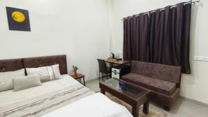 een slaapkamer met een bed, een stoel en een bureau bij Sukoon The Legacy in Ujjain