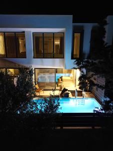 una piscina frente a una casa por la noche en serene villas halkidiki - Cfront private pool en Epanomi