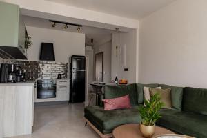 a living room with a green couch and a kitchen at Chelmis Sea Front Apartments - Atlantis in Argostoli