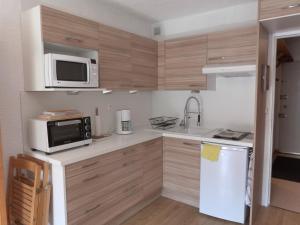 een keuken met houten kasten en een witte koelkast bij Studio au cœur du Sauze - La grande Chaume in Enchastrayes