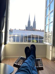 a person sitting on a bench in front of a window at Cœur de Ville Idéal et charmant 4 pers in Clermont-Ferrand