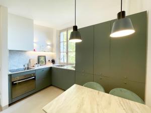 uma cozinha com armários verdes e uma mesa com cadeiras em CozyClouds vicino Piazza del Campo em Siena