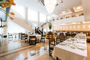 a dining room with tables and chairs and windows at Dinamo Hotel Baku in Baku