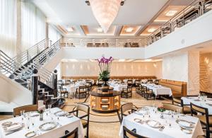 a restaurant with white tables and chairs and a staircase at Dinamo Hotel Baku in Baku
