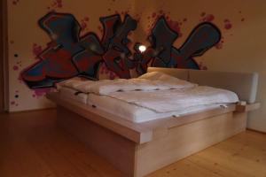 Bett in einem Zimmer mit einer mit Graffiti bedeckten Wand in der Unterkunft Haus Tanegg in Innsbruck