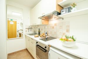 a kitchen with white cabinets and a bowl of fruit on the counter at Umag center apartment parking by Rentistra in Umag