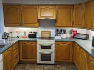 a kitchen with wooden cabinets and a white stove top oven at Saltwater Cottage in Dunseverick