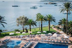 een resort met een zwembad, stoelen en palmbomen bij THB Los Molinos Adults Only in Ibiza-stad