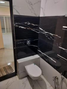 烏賈因的住宿－Shiv Shakti Homestay，一间带卫生间和黑色大理石墙的浴室